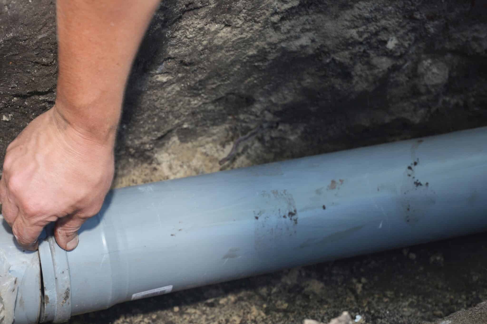 Contractor installing house sewer pipe in the ground trench, Sewer Line Damage.