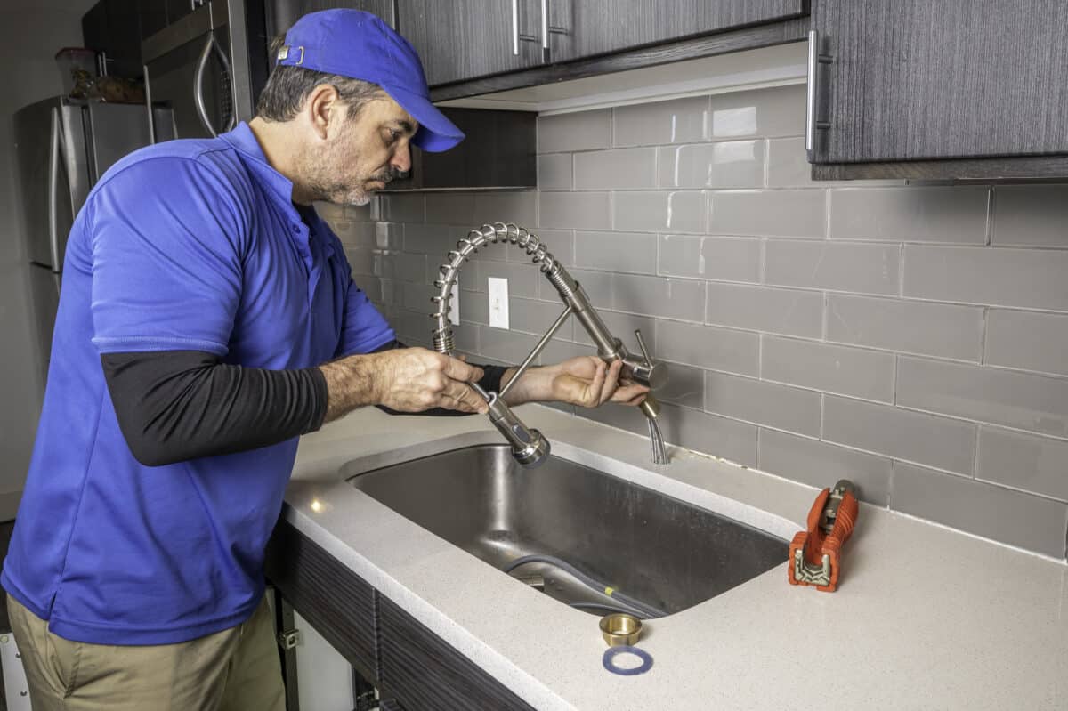 Plumber removing or installing a kitchen faucet, Plumbing Services.